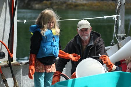 Shipley Carlson watches on as her grandfather, Sam Carlson, and her father, Matt Carlson, clean recently caught fish. (National Geographic/Wayne Moss)