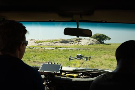 A drone takes off from the front bonnet of a safari Jeep whilst the pilot watches. (credit: National Geographic/Jigar Ganatra)