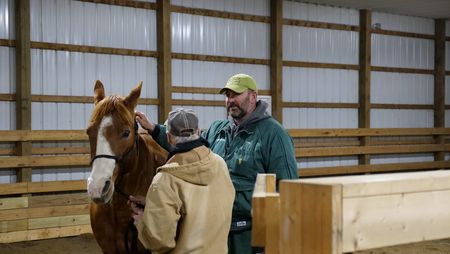 Logan McClelland comforts his horse Stylin' and discusses his care with Dr. Ben Schroeder. (National Geographic)