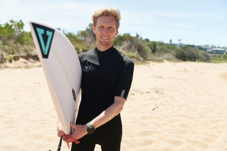 Brett Connellan with his surfboard at Bombo Beach. (National Geographic/Justine Kerrigan)