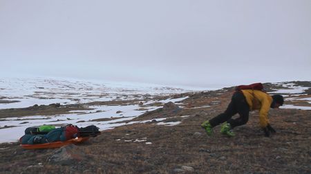 Eric McNair Landry pulling a sled across terrain where snow has melted too much to allow for skiing.  (Mandatory photo credit: Sarah McNair Landry)
