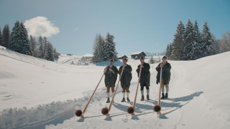 Four horn players in typical South Tyrolean attire play their horns, outside restaurant Gostner Schwaige, on the snow.  (credit: National Geographic)