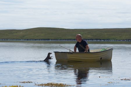 Molly leaps out of the water to the transom of Billy's dinghy as he looks on from the boat. (National Geographic/Johnny Rolt)