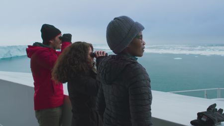 Eric Stackpole, Melissa Marquez and Zoleka Filander look out from the OceanXplorer across the ice towards a glacier in Svalbard. (National Geographic)