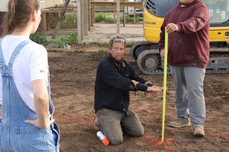 Beth Pol and Ben Reinhold discuss their plans for the garden while Andrew Hutton holds a tape measure to provide an example height of the new pond's waterfall. (National Geographic)