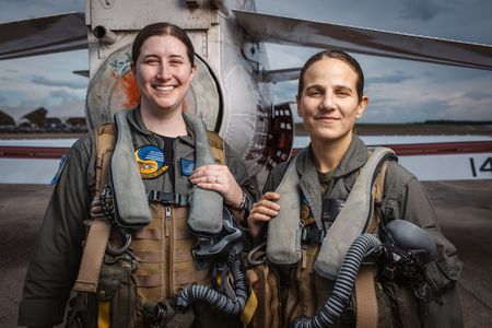Students LT Carissa Meinster and Captain Steph Harris pose behind a T-45. (Credit: National Geographic/Freddie Claire)