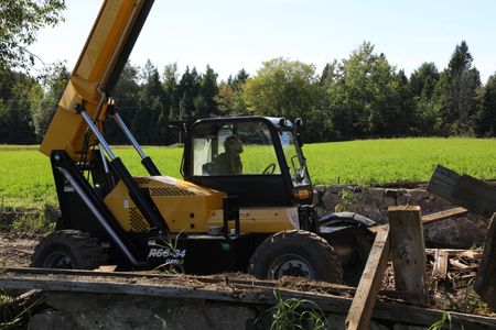 Ben Reinhold uses a telehandler to lift and transport heavy lumber from the old barn takedown. (National Geographic)